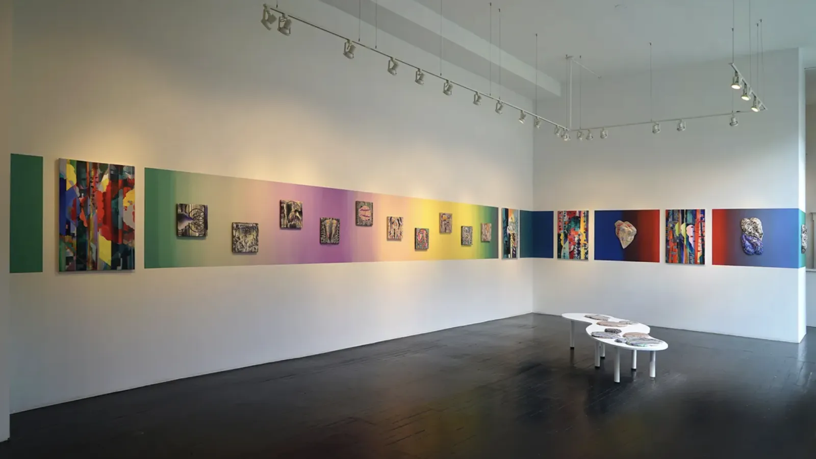 Art gallery with many colorful works hanging closely to one another 