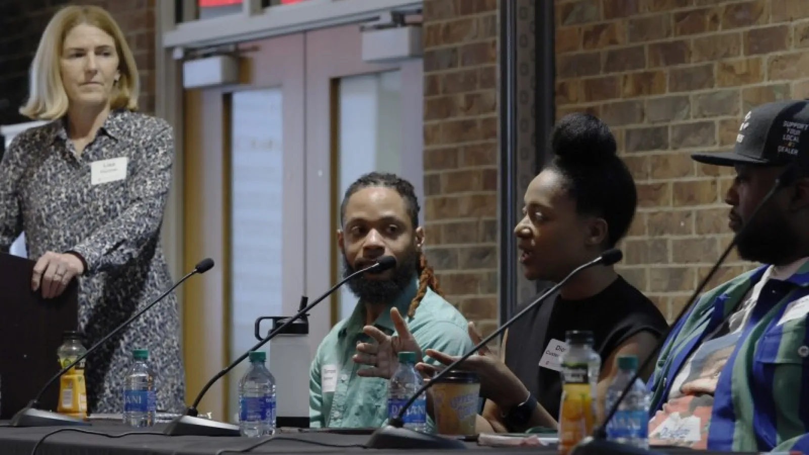 Three panelists at the symposium, along with the moderator standing to the left