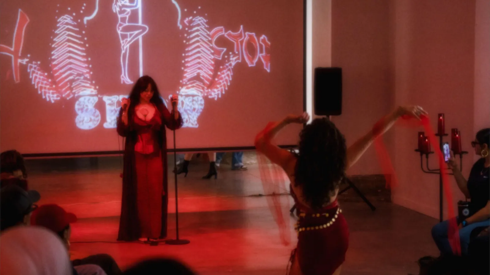 christina singing at the mic while miriam dances at the vessels in red opening reception