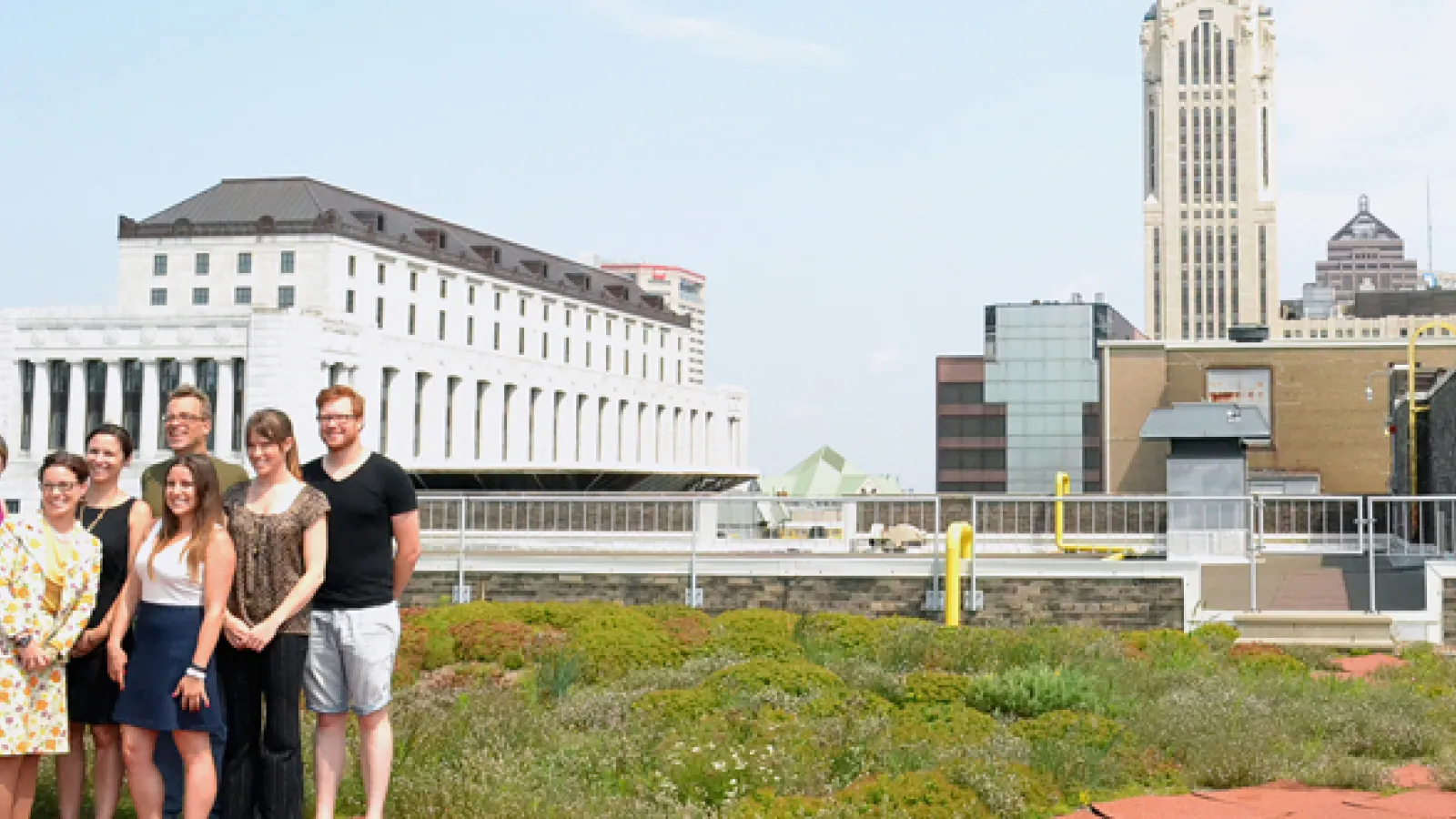A group of people pose in front of the Columbus skyline on a Rooftop Garden Tour.