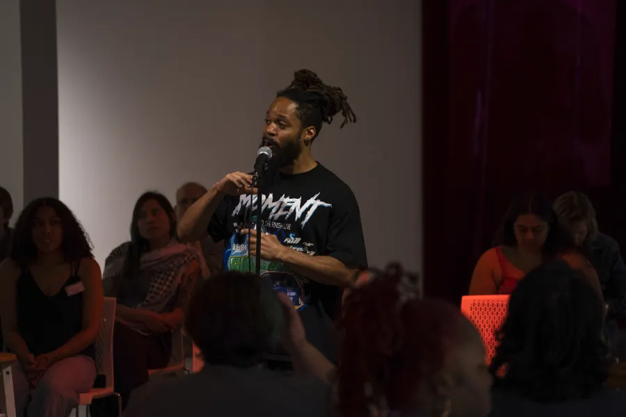 A man standing at a microphone in front of a crowd of people