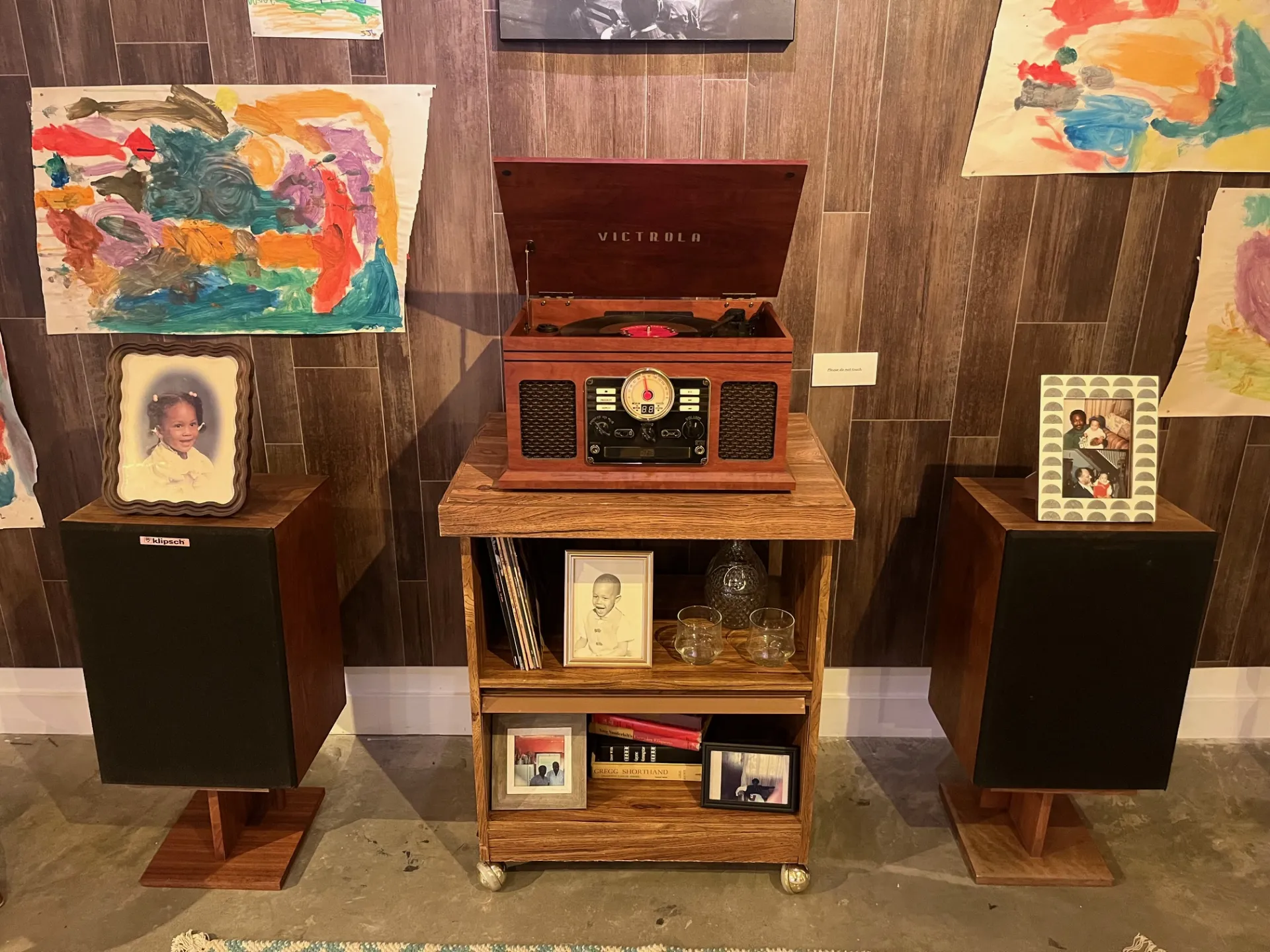 A vintage Victrola record player on top of a rolling side table, with a floor speaker on each side of the table.