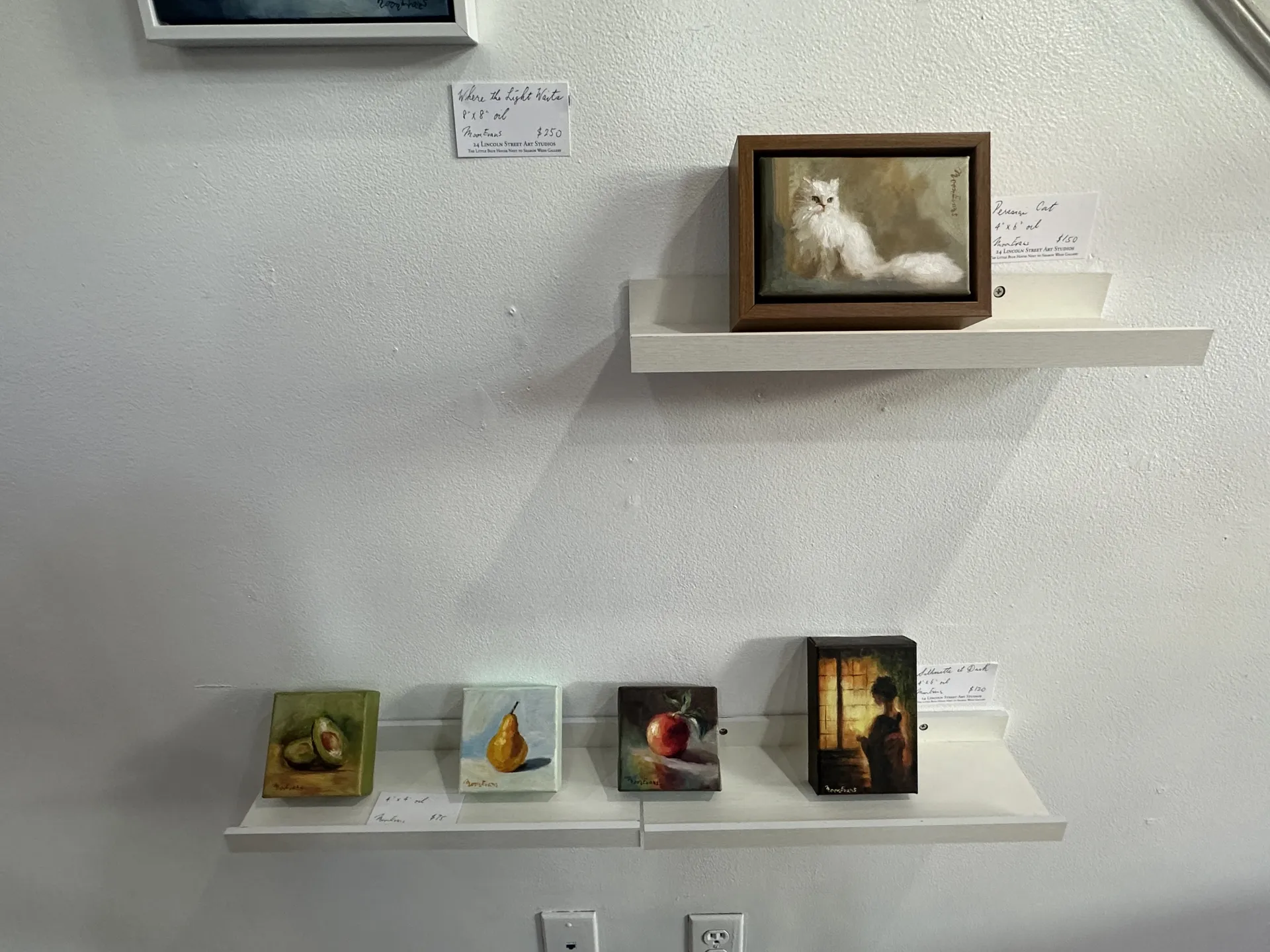 small paintings of fruits and a white cat