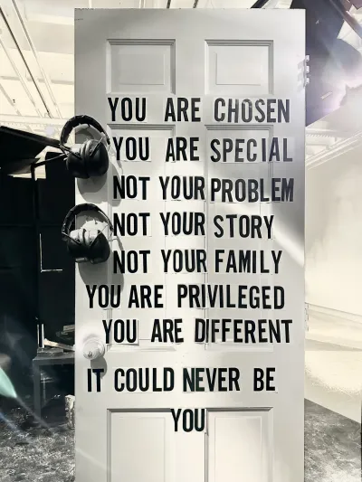 White door that says You are chosen, you are special, not your problem, not your story, not your family, you are privileged, you are different, it could never be you