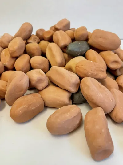 A pile of one hundred terracotta clay dates on a white pedestal