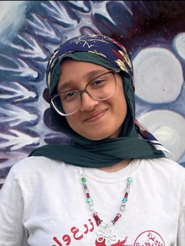Haadia smiling on a colorful background.