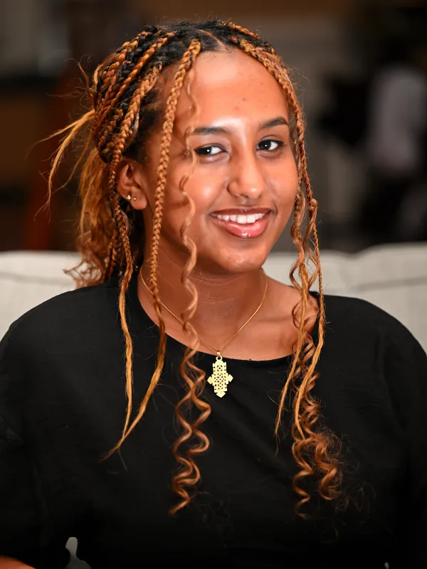 BItania smiling in a black shirt with gold necklace