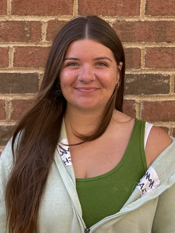 Brendi smiling in front of a brick wall