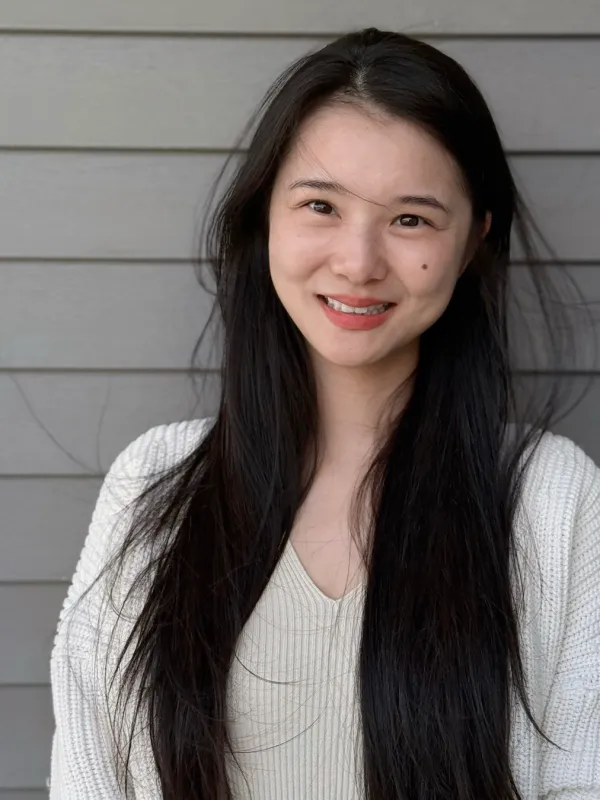 Xiaoxiao smilling with long black hair and a white sweater