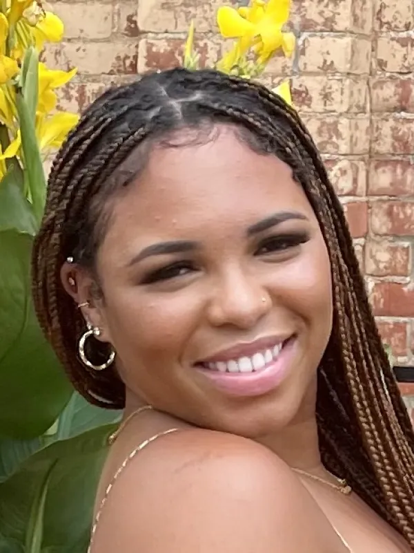 Juanaya smiling over her shoulder in front of a brick wall.